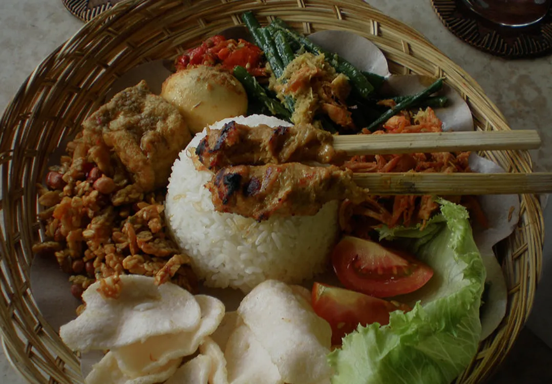 Plato de nasi campur con arroz, verduras y satay