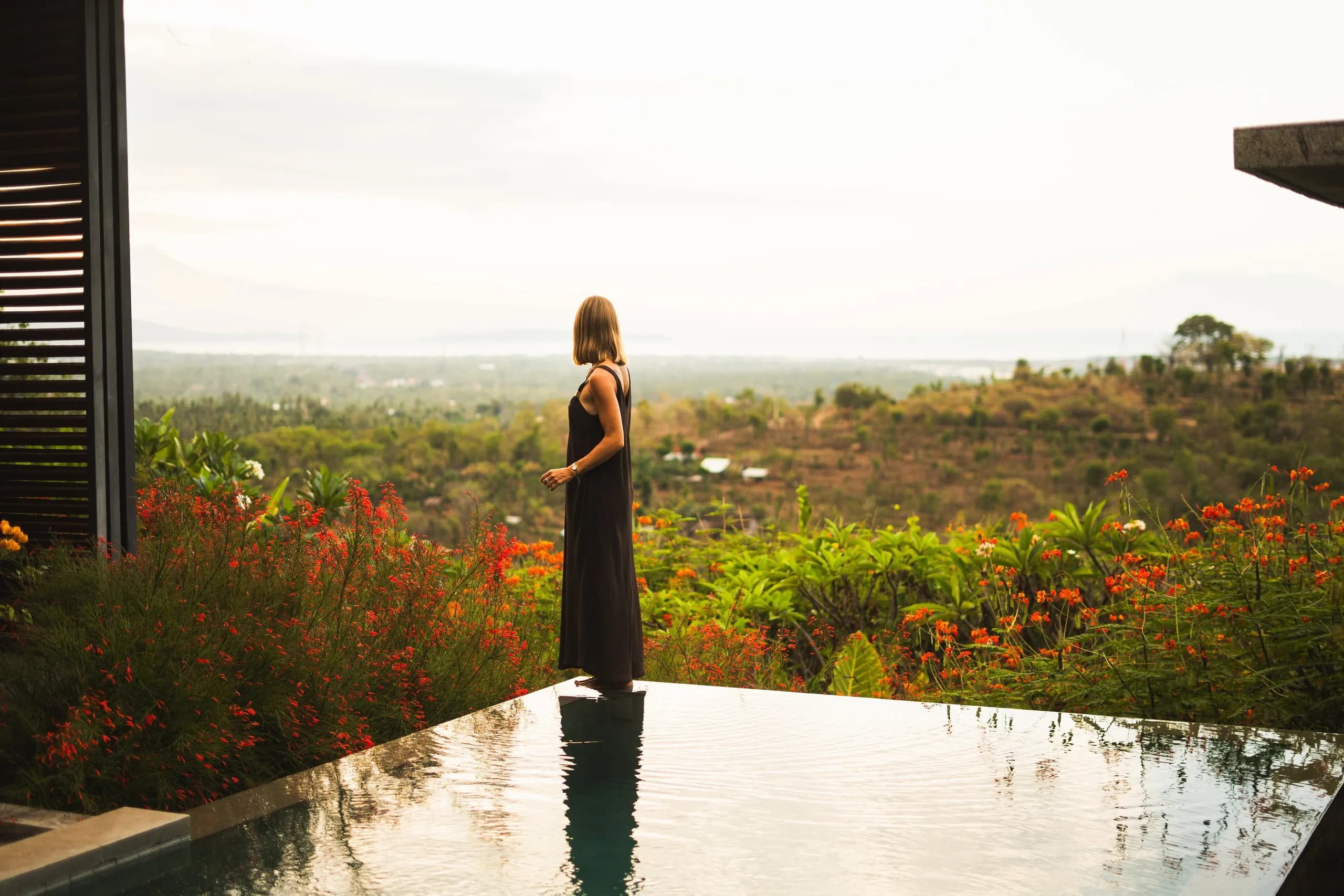 Mujer mirando el paisaje desde una piscina infinita