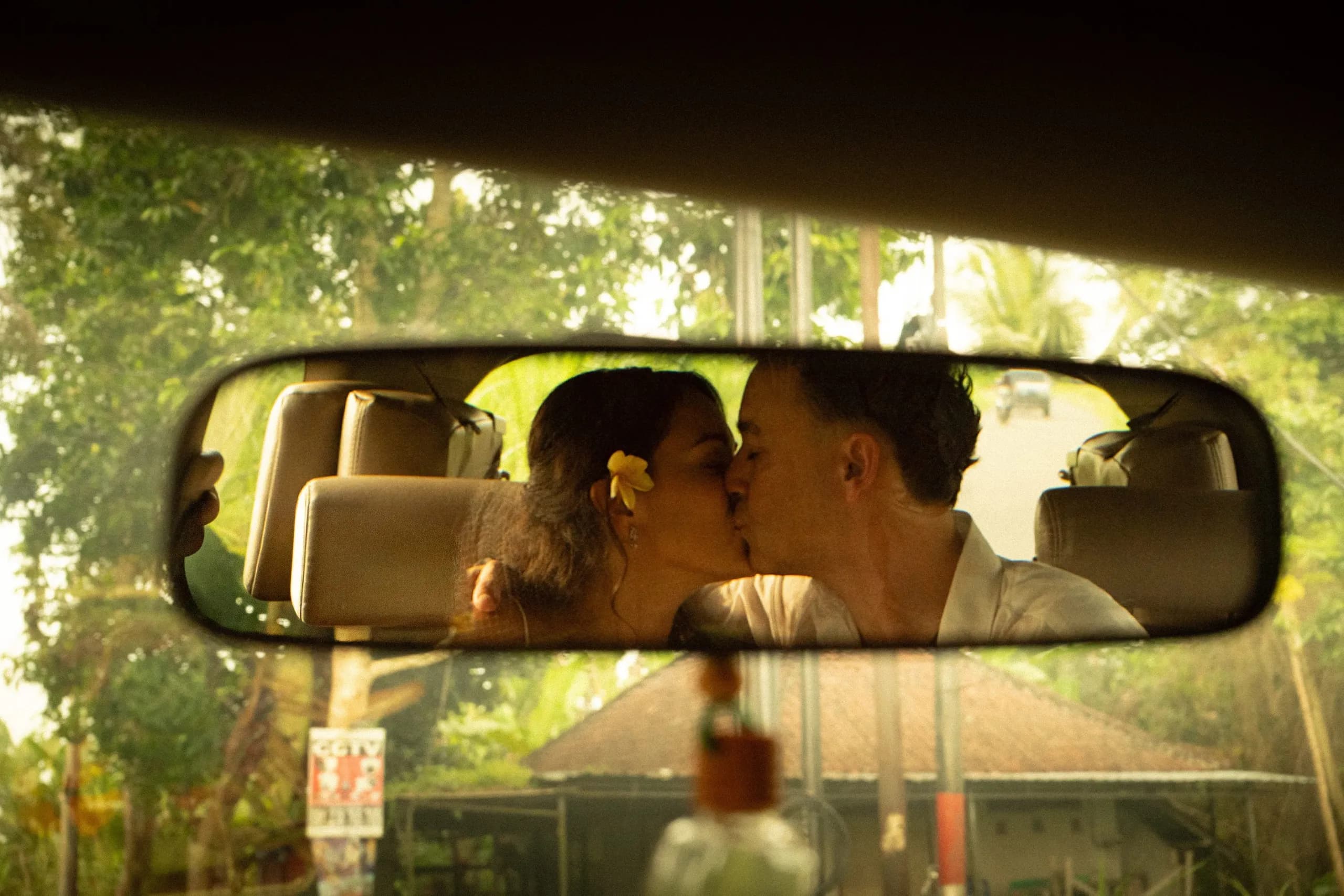 Pareja besándose, reflejada en el retrovisor de un coche